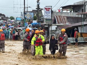 Petugas mengevakuasi warga yang terjebak banjir.
