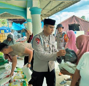 Personel Brimob Batalyon C menyalurkan bantuan paket sembako kepada warga Desa Aek Ngadol.